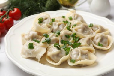 Beyaz masada yeşil soğanlı leziz pelmeni, yakın plan.