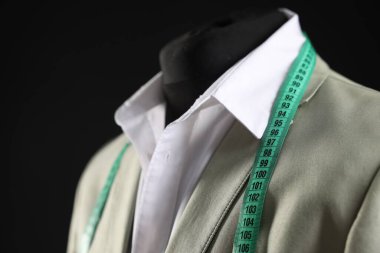 Male mannequin with jacket, shirt and measuring tape on black background, closeup clipart