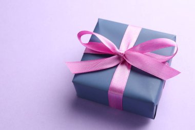 Menekşe arka planında pembe fiyonklu güzel hediye kutusu, yakın plan. Metin için boşluk