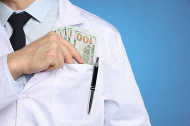 Yozlaşma konsepti. Doktor cebine dolar banknotları koyuyor mavi arka planda, yakın plan