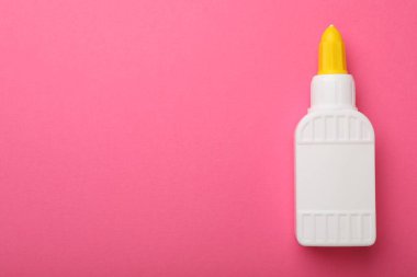Bottle of glue on pink background, top view. Space for text