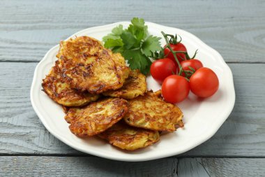 Gri ahşap masada patatesli gözleme, domates ve maydanoz, yakın plan.