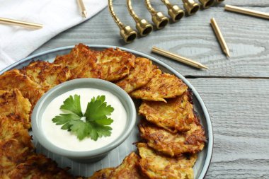 Lezzetli patates krepleri, menorah ve gri ahşap masada mumlar, yakın plan. Hanuka bayramı yemekleri.