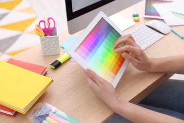 Tasarımcı tablet üzerinde çalışıyor. Kapalı masa, yakın plan.