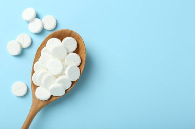 Antibiyotik haplar ve açık mavi arka planda kaşık. Metin için boşluk