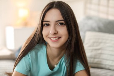 Evdeki yatakta gülümseyen genç kızın portresi.