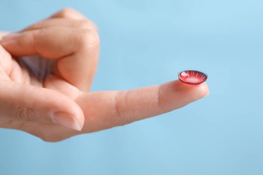 Açık mavi arkaplanda renk lensi tutan kadın, yakın plan