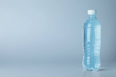 Açık mavi zemin üzerinde plastik su şişesi, metin için boşluk