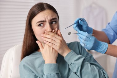 Dental phobia. Dentist working with scared woman in clinic, closeup clipart