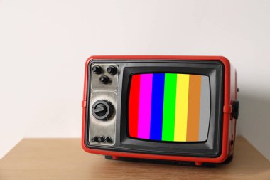 Retro TV set with test pattern on wooden table near white wall. Color bars on screen. No signal clipart