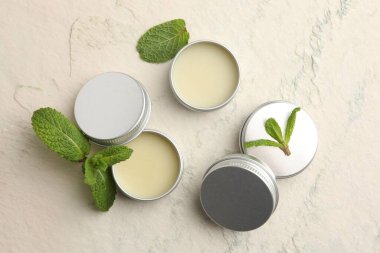 Nane dudak kremi ve bej desenli arka planda yeşil yapraklar. Kozmetik ürünü