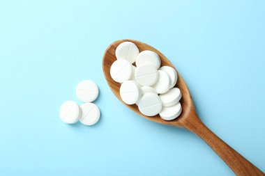 Antibiyotik haplar ve açık mavi arka planda kaşık. Metin için boşluk