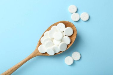 Antibiyotik haplar ve açık mavi arka planda kaşık, düz uzanma