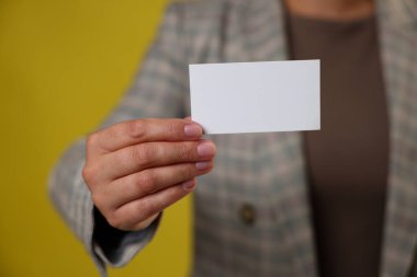 Sarı arka planda boş kartviziti olan bir kadın, yakın plan. Tasarım için model