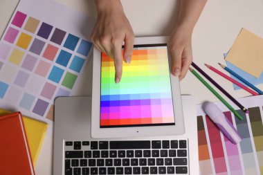 Web sitesi tasarımcısı beyaz masadaki tablet üzerinde renk paleti ile çalışıyor, üst görünüm