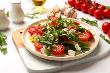 Lezzetli salata roka, peynir ve sebze beyaz masada, yakın plan.