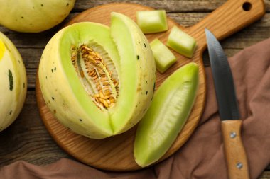 Fresh whole and cut honeydew melons on wooden table, flat lay clipart