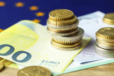 Avro banknotları, madeni paralar ve Avrupa Birliği bayrağı masada, yakın plan