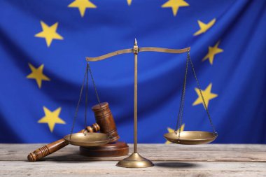 Adalet terazisi ve hakimin tokmağı Avrupa Birliği bayrağına karşı ahşap masada