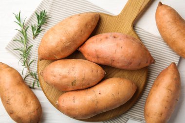 Beyaz ahşap masada taze çiğ patates ve biberiye.