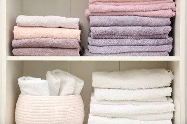 Home textile organization. Folded towels on shelving unit indoors, closeup clipart