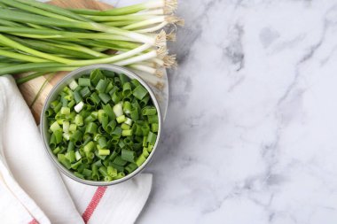 Kasede doğranmış yeşil soğan ve beyaz mermer masa üzerinde sapları, üst manzara. Metin için boşluk