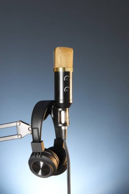 Karanlık arka planda mikrofon ve kulaklıkla bekle. Ses kaydı ve takviye