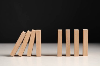 Domino etkisi. Tahta bloklar beyaz masaya düşüyor.