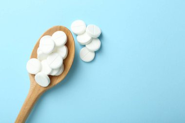 Antibiyotik haplar ve açık mavi arka planda kaşık. Metin için boşluk