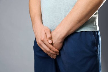 Cinsel yolla bulaşan hastalıklar. Gri arka planda semptomlardan muzdarip bir adam, yakın plan