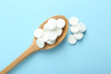 Antibiyotik haplar ve açık mavi arka planda kaşık, düz uzanma