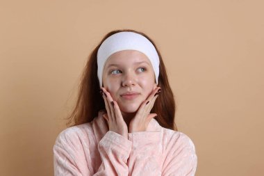 Bej arkaplanda saç bandı olan genç bir kız.