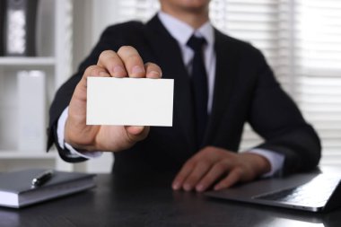 Ofisteki masada boş bir kartvizit tutan adam, yakın plan. Tasarım için model