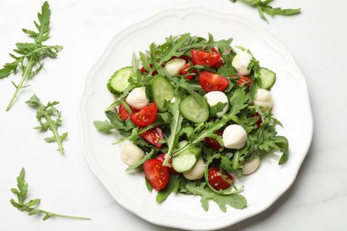 Lezzetli salata roka, mozzarella, domates ve salatalık beyaz mermer masada, düz konum