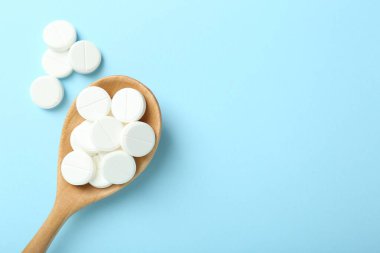 Antibiyotik haplar ve açık mavi arka planda kaşık. Metin için boşluk