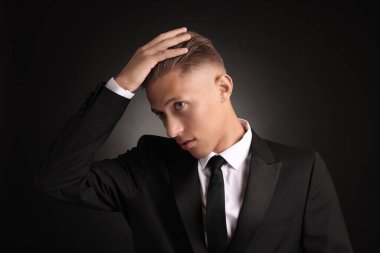 Siyah arka planda şık saç kesimi olan kendine güvenen genç bir adam.