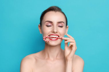 Açık mavi arka planda Noel şekeri bastonlu kadın