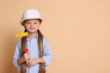 Bej arka planda paten fırçası olan sert şapkalı küçük bir kız, mesaj için yer. Geleceğin mesleğini hayal etmek.