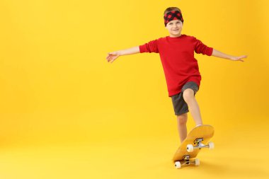 Sarı arka planda kaykaylı küçük çocuk, mesaj için yer var.