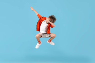 Mutlu küçük çocuk açık mavi arka planda zıplıyor