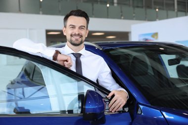 Yeni mavi arabanın yanındaki mutlu adam kuaförde