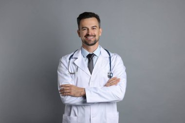 Gri arka planda steteskobu olan gülümseyen doktor.
