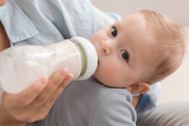 Mother feeding her little baby from bottle, closeup