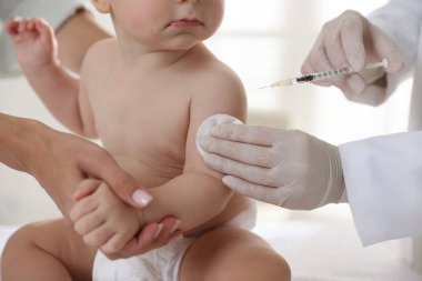 Pediyatrist klinikte bebek aşılıyor.