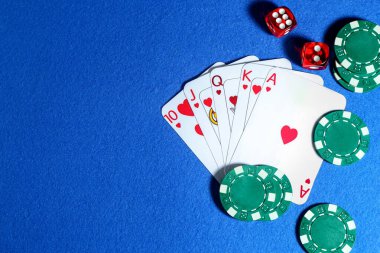 İskambil kağıtları, poker fişleri ve küpleri mavi masada, düz yerde. Metin için boşluk