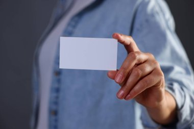 Gri arka planda boş kartviziti olan bir kadın, yakın plan. Tasarım için model