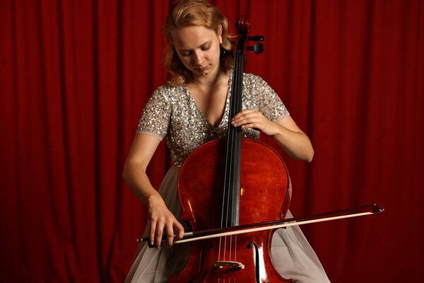 Beautiful young woman playing cello on stage