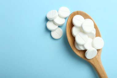 Antibiyotik haplar ve açık mavi arka planda kaşık. Metin için boşluk