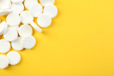 Sarı arka planda antibiyotik hapları yığını, üst manzara. Metin için boşluk