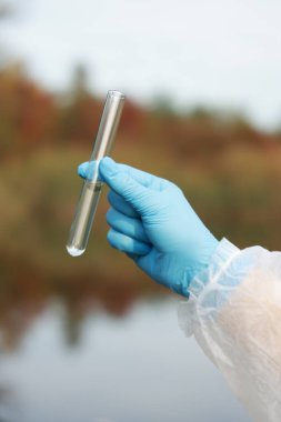 Su kalitesinin incelenmesi. Araştırma görevlisi test tüpünü dışarıda tutuyor, yakın plan.